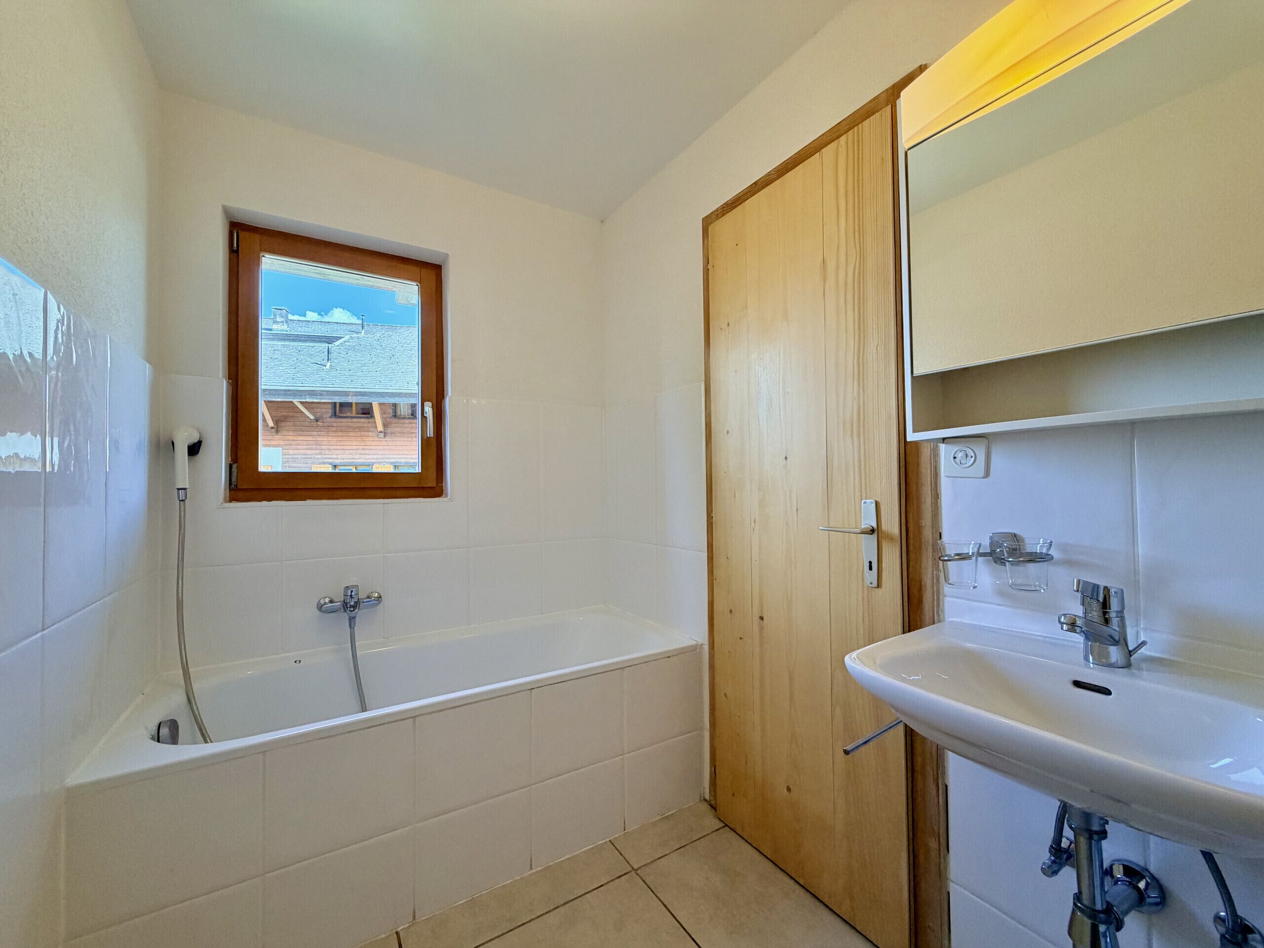 Une salle de bain avec une baignoire, un lavabo et une fenêtre.