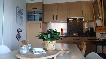Cozinha moderna com armários de madeira, uma mesa de jantar com um jogo americano e um vaso com planta.