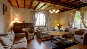 A cozy living room with wooden beams, a round wooden table, and two sofas. - Spacious and cozy family gîte, pets allowed, up to 10 people (Saint-Martin-la-Sauveté)