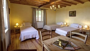 A cozy room with wooden beams, two single beds, a table with magazines, and a window with curtains. - Spacious and cozy family gîte, pets allowed, up to 10 people (Saint-Martin-la-Sauveté)