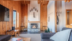 A cozy living room with a fireplace, wooden walls, and a TV mounted on the wall. - Fontannets 008 QUIET & SUPERIOR chalet 10 pers (Salins)