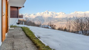 A snow-covered pathway leading to a building with a wooden door and a balcony overlooking snow-capped mountains. - Fontannets 008 QUIET & SUPERIOR chalet 10 pers (Salins)