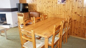 A wooden dining table with six chairs, a television on a stand, and a fireplace. - Mélèzes S 033 - SKI LIFT apartment 8 pers (Veysonnaz)