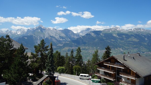A mountain lodge with a balcony and a view of snow-capped peaks.