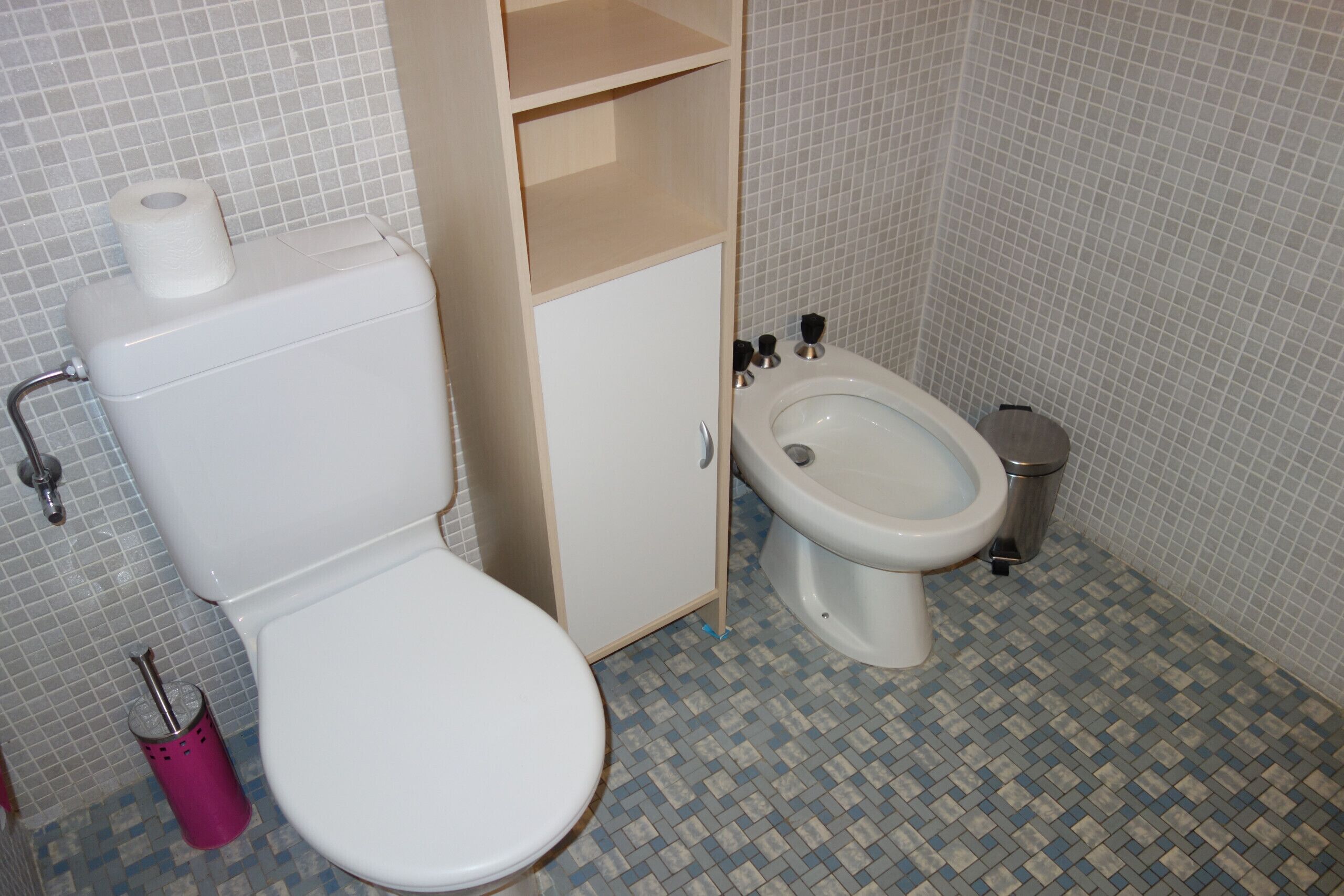 Ein Badezimmer mit Toilette, Bidet und einem Schrank.