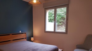 A bedroom with a bed, a chair, a window, and a lamp. - Independent house for 6 in Barneville-Carteret with WiFi and bikes (Barneville-Carteret)