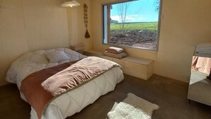A bedroom with a large bed, a bench, a window with a view of the outdoors, and a small table. - Authentic House with Spa and Pets Allowed (Saint-Forgeux-Lespinasse)