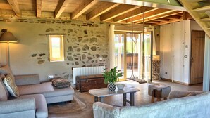 A cozy living room with a stone wall, wooden beams, a sofa, a table, and a swing. - Authentic House with Spa and Pets Allowed (Saint-Forgeux-Lespinasse)