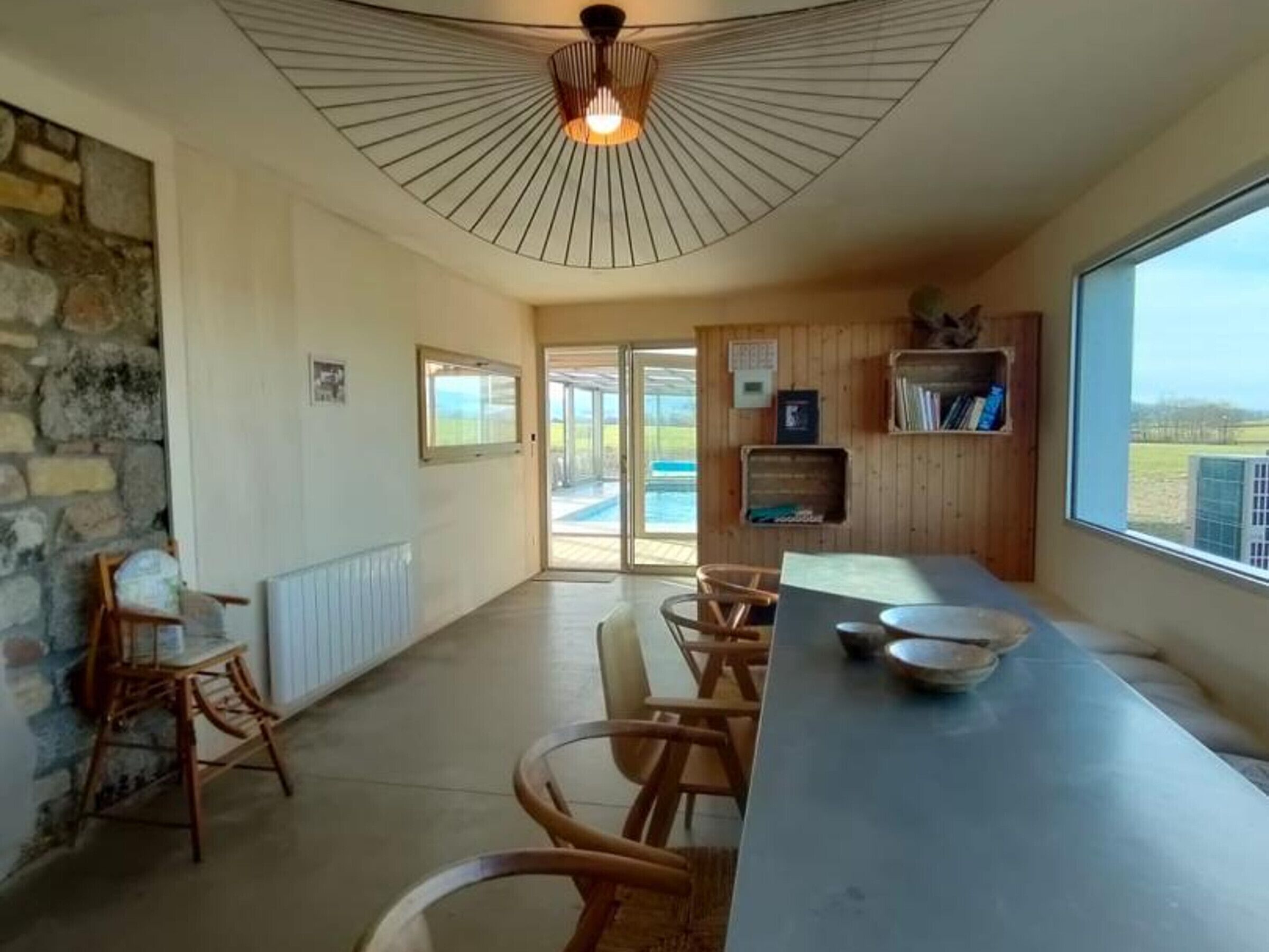 A modern kitchen with a long counter, wooden chairs, and a view of the outdoors.