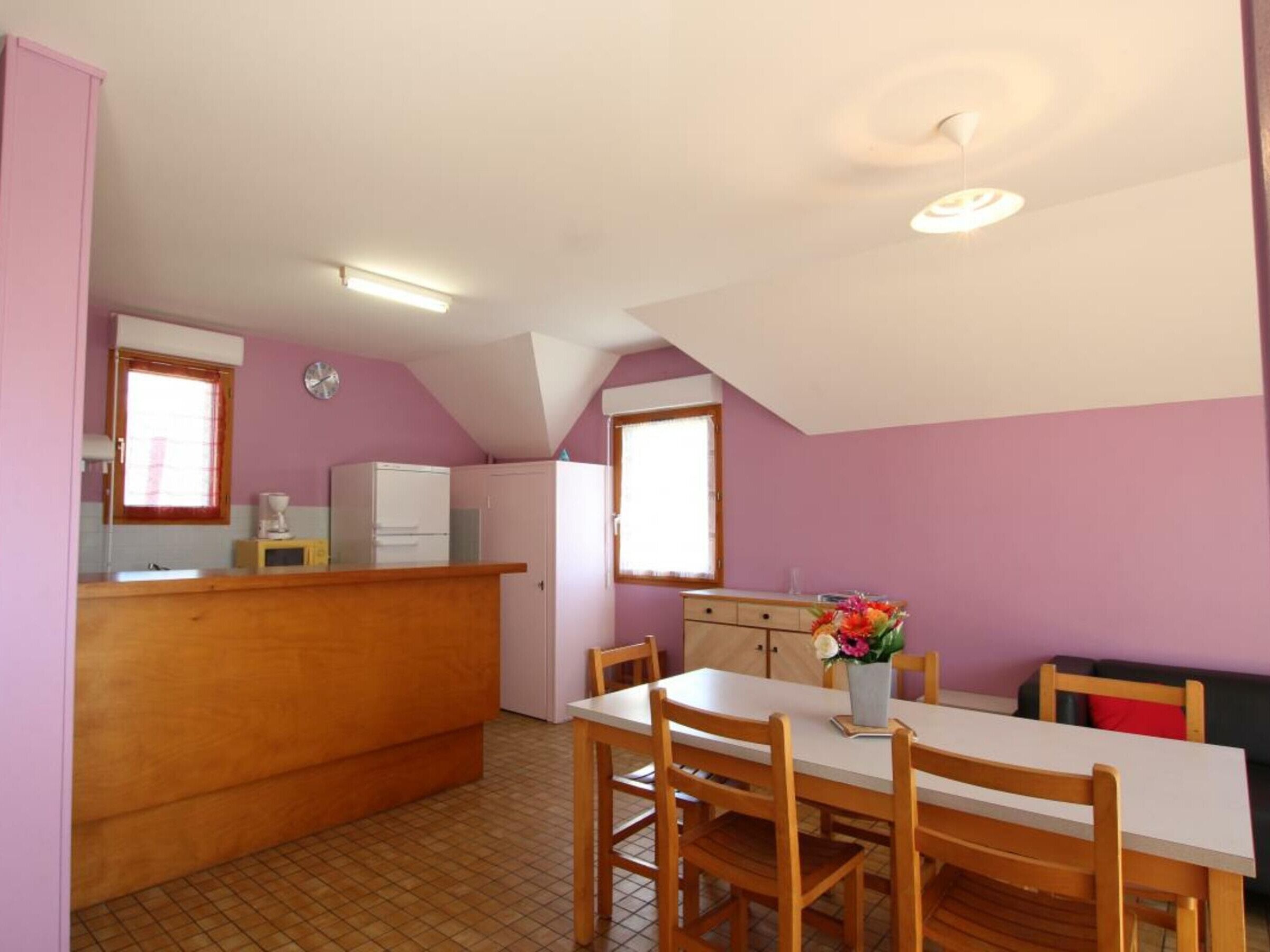 Cocina compacta con comedor, refrigerador, pileta y ventana.
