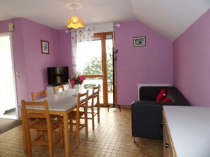 Un coin repas avec une table et des chaises, un téléviseur et un canapé.