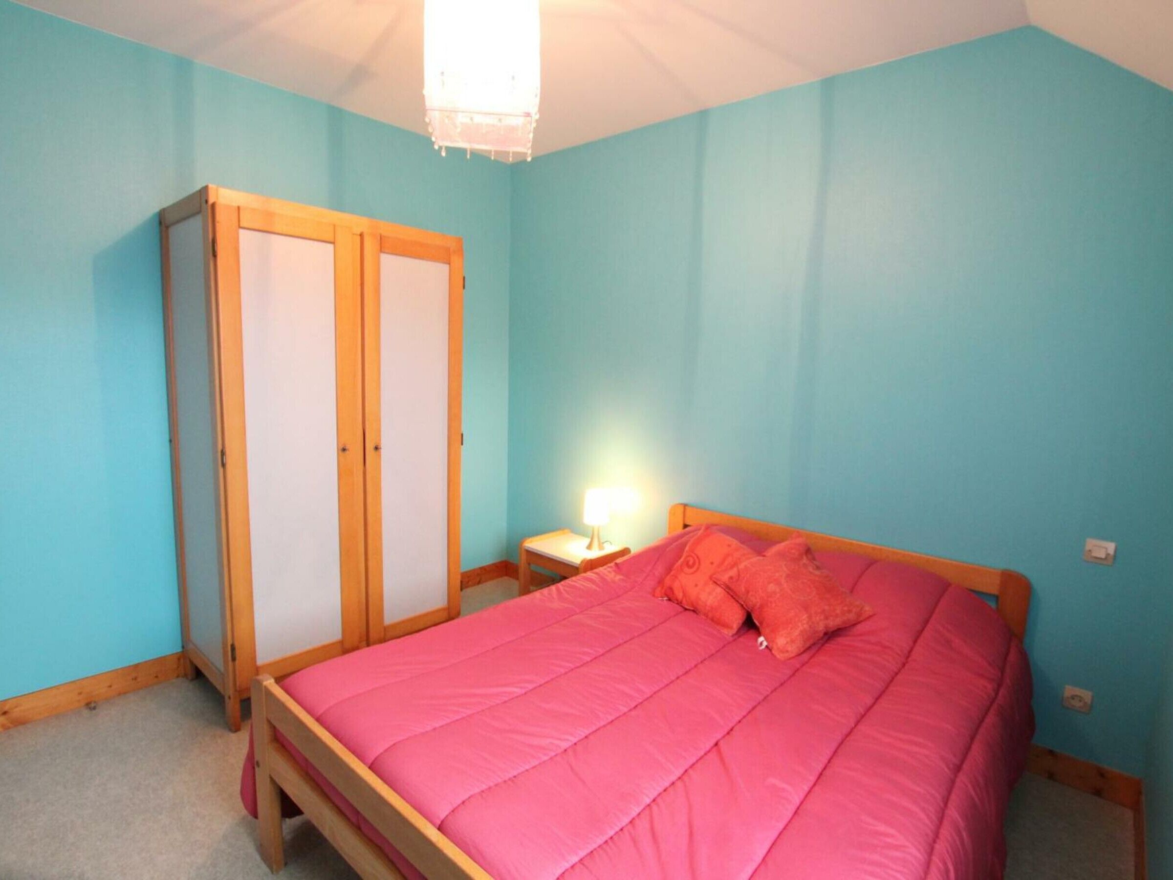 Un dormitorio con cama, armario y mesita de noche.