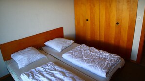 A double bed with white bedding in a room with wooden walls and a wooden headboard. - Mont-Rouge E 010 - VIEW apartment 8 pers (Veysonnaz)