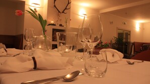 A dining table set with wine glasses, a vase with a flower, and cutlery. - Beautiful modern villa with large suites in the middle of the mountains (Oščadnica )