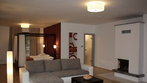 A modern living room with a grey sofa, a coffee table, a fireplace, and a large window with curtains. - Beautiful modern villa with large suites in the middle of the mountains (Oščadnica )