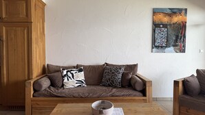 A cozy living room with a brown sofa, a wooden coffee table, and a wall-mounted painting.