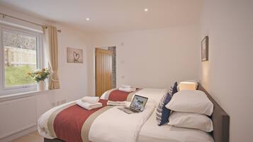 Habitación de hotel con una cama, una computadora portátil y una ventana con cortinas.