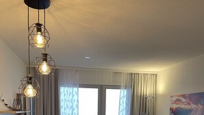 Ein modernes Wohnzimmer mit einem Holzesstisch, Stühlen, einem grauen Sofa und einem farbenfrohen Teppich.