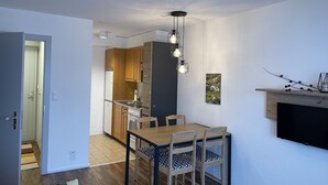 Eine kompakte Küche mit Holzausbau, einem eingebauten Backofen und einem Essbereich mit Tisch und Stühlen.