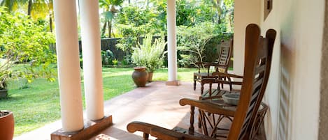 A covered patio with wooden furniture and a garden view.