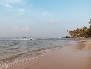 A beach with calm waves, a sandy shore, and a row of palm trees. - Lovely Villa near Unawatuna Beach. (Unawatuna)