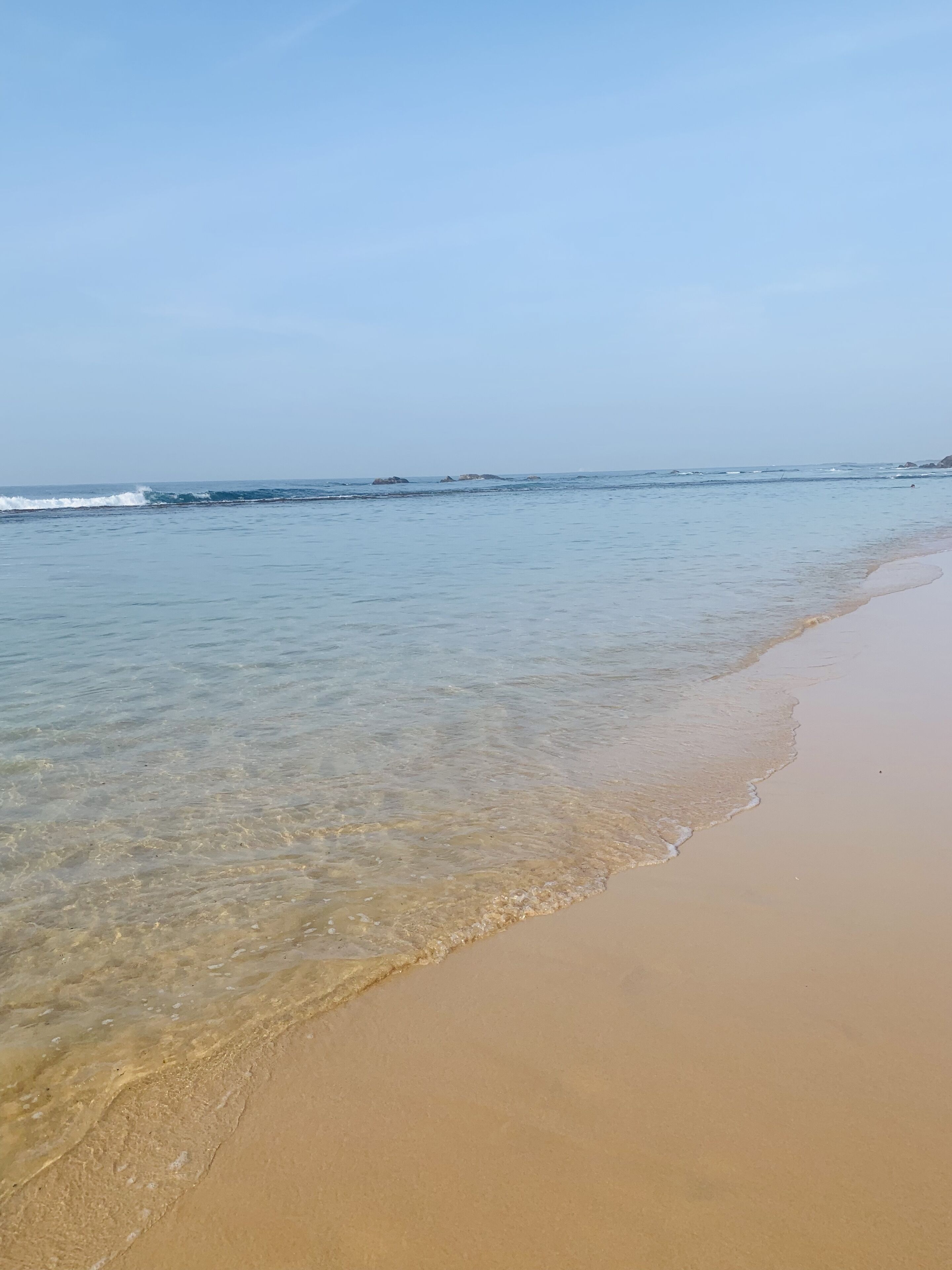 Ein Strand mit klarem, flachen Wasser und einem Sandufer.