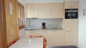 Una cocina compacta con armarios de madera, una cafetera y un lavabo.