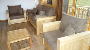 Un salón amueblado con madera, con dos sofás y una mesita.