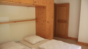 A bedroom with a bunk bed, a wooden wardrobe, and a door.