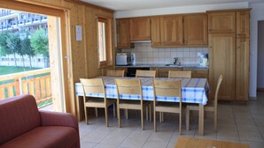 A kitchen with wooden cabinets, a tiled backsplash, and a dining table with chairs.