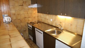 Una cocina compacta con estufa, lavavajillas y pileta.