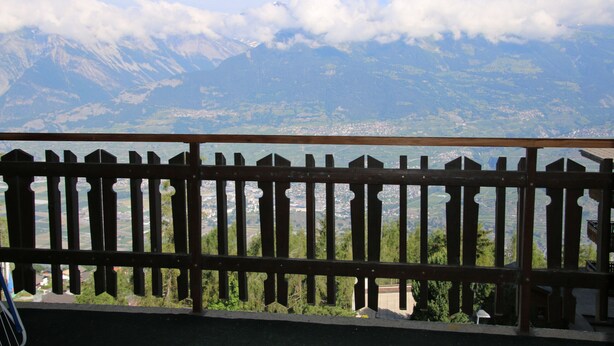 Un balcón con vista a un paisaje montañoso y una masa de agua.