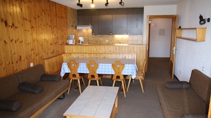 Una habitación acogedora con paredes de madera, una mesa de comedor con sillas y dos sofás.