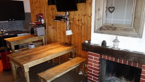 Een rustiek interieur met een houten tafel, een bank en een bakstenen open haard.