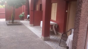 A covered outdoor area with a tiled floor, a small tree, and a table with a chair. - private room with bathroom (Touama)