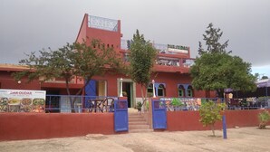 A red building with a sign for 'DAR OUDAR Hotel, Restaurant, Café'. - private room with bathroom (Touama)