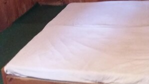A room with wooden walls and a single bed with a white mattress. - Mountain Top View Homestay (Banjar)