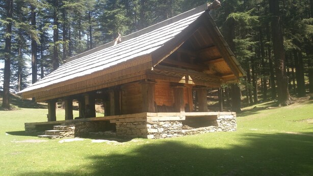 A wooden cabin with a sloped roof, stone foundation, and a porch area. - Mountain Top View Homestay (Banjar)
