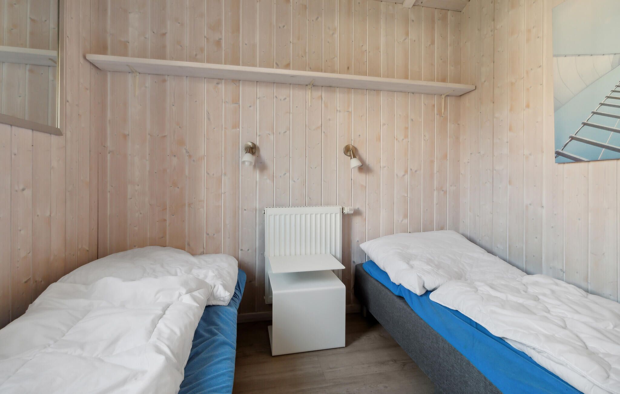 Een kamer met twee eenpersoonsbedden, een witte radiator en houten wanden.