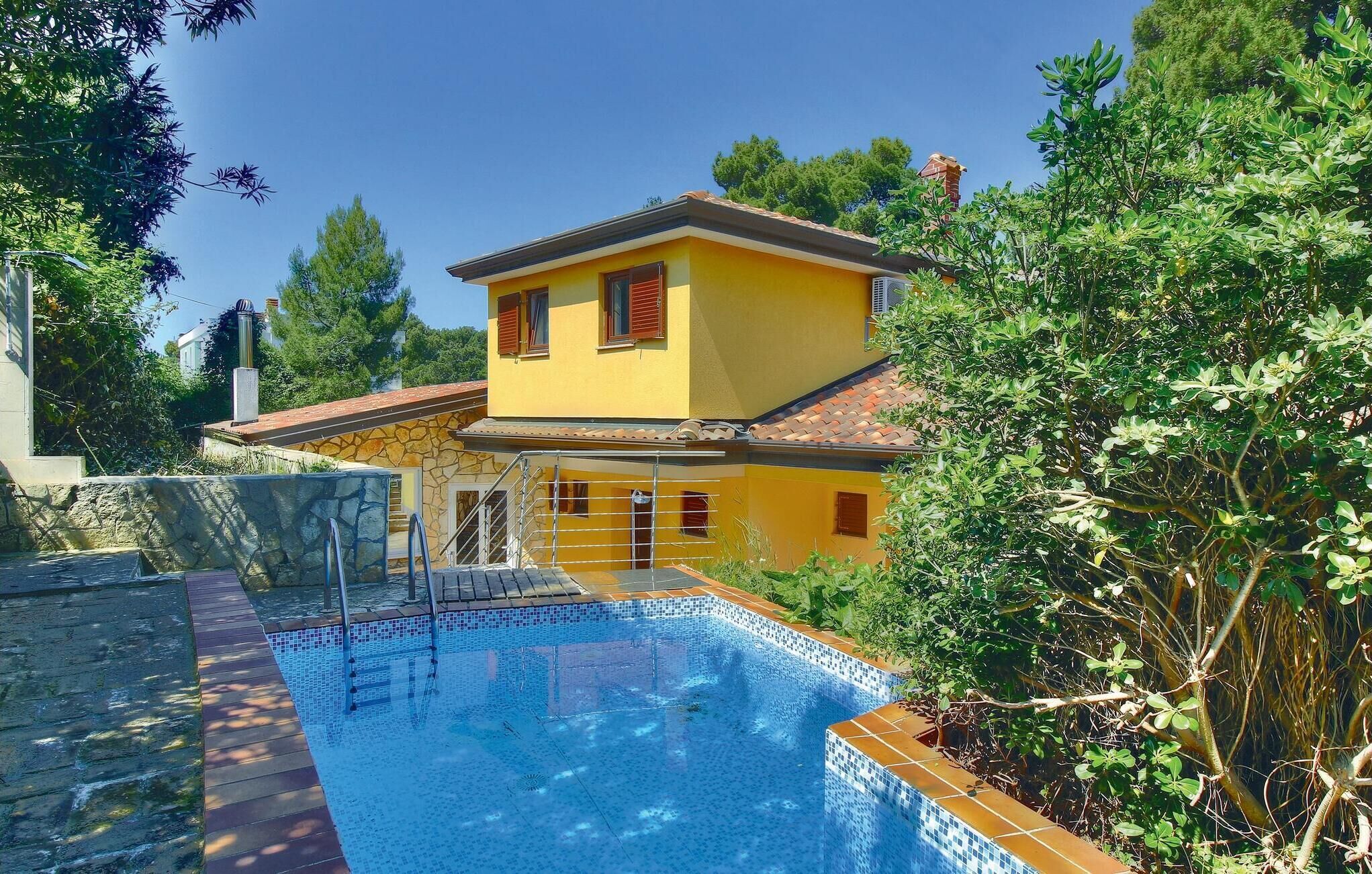 Uma vila amarela com piscina, paredes de pedra e vegetação exuberante.