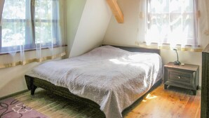 Un dormitorio con cama, mesita de noche, lámpara y ventana con cortinas.