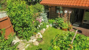 Un jardín con una casa de madera, un camino de piedra y diversas plantas.