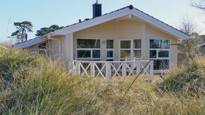 Et hvidt hus med saddeltag, store vinduer og et hvidt hegn foran.