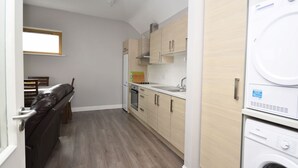 Una cocina compacta con armarios de madera, horno empotrado y lavadora.