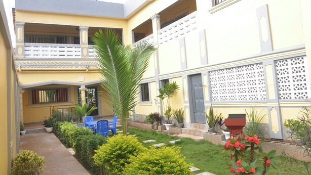 A two-story building with balconies, a garden area with potted plants, and outdoor seating.