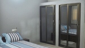 A bedroom with a bed, a ceiling fan, and a sliding glass door leading to a balcony.