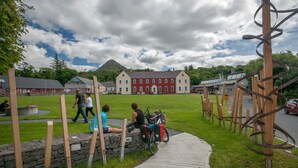 A stone wall with wooden posts, a red building in the background, and a clear sky. - Apartment 702 Letterfrack - sleeps 4 guests  in 3 bedrooms (Unknown)