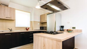 Een moderne keuken met een centraal eiland, donkere kasten, een magnetron, een koffiezetapparaat en een schaal fruit op het aanrecht.