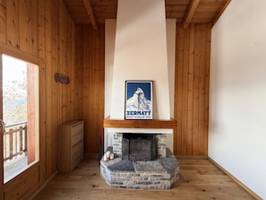 Een houten interieur met een open haard, een poster en een houten deur.