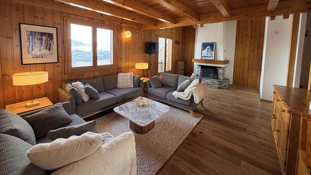 Un accogliente interno di una baita con pareti in legno, un caminetto e un divano.